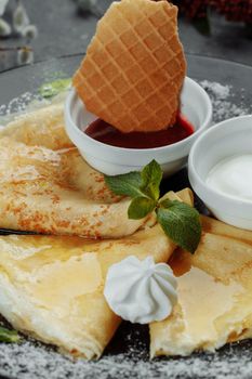 Pancakes with strawberries and creme black plate.