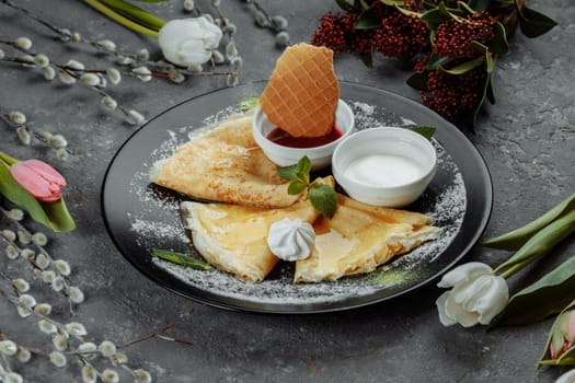 Pancakes with strawberries and creme black plate.