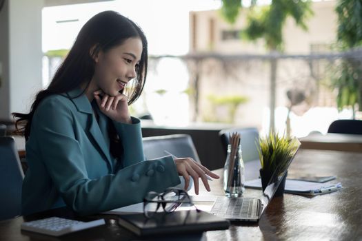 Asian business woman using laptop talk to colleagues for briefing business plan in video call. finance fund investment concept