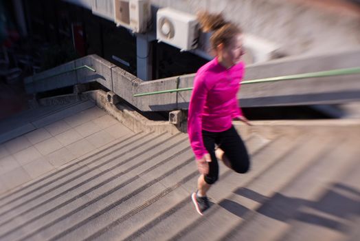 sporty woman running onsteps at early morning jogging