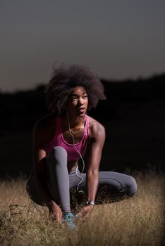 young African american woman runner tightening shoe lace in nature  Fitness, people and healthy lifestyle