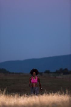 young African american woman runner with headphones jogging outdoors in nature beautiful summer night - Fitness, people and healthy lifestyle