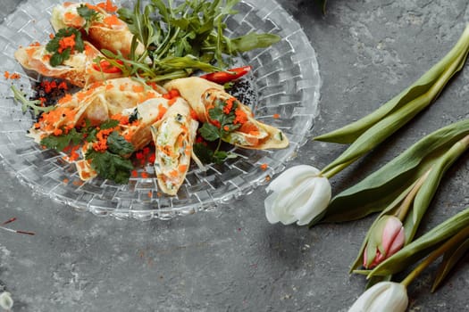 thin pancakes with caviar and salmon, rolled into rolls.