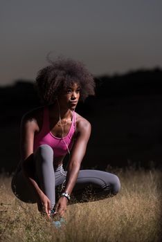 young African american woman runner tightening shoe lace in nature  Fitness, people and healthy lifestyle