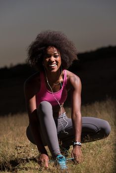 young African american woman runner tightening shoe lace in nature  Fitness, people and healthy lifestyle