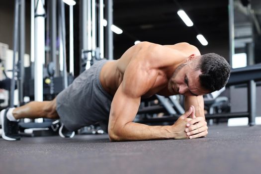 Portrait of a fitness man doing planking exercise in gym