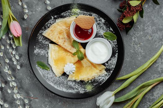 Pancakes with strawberries and creme black plate.