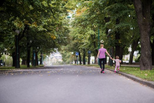 young sporty mother and little daughter jogging in a city park outdoor sports and fitness