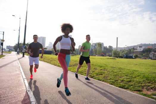 multiethnic group of young people on the jogging beautiful morning as the sun rises in the streets of the city