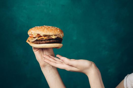 hamburger in hands close-up fast food green background. High quality photo