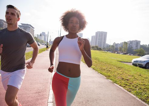 multiethnic group of young people on the jogging beautiful morning as the sun rises in the streets of the city