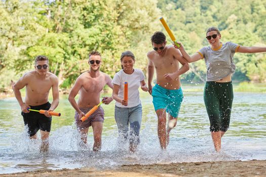 Summer joy group of happy friends having fun while running and splashing on river