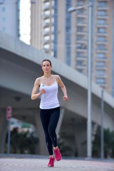 Running in city park. Woman runner outside jogging at morning with Dubai urban scene in background