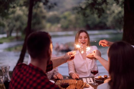 group of happy friends having picnic french dinner party outdoor during summer holiday vacation near the river at beautiful nature