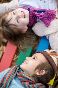 cutte little girl and boy in childrens park having fun and joy while playing in playground on autumn cloudy day