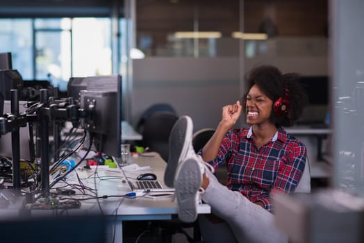 portrait of a young successful African American beautiful woman who enjoys spending a quality and joyful time while working in a large modern office