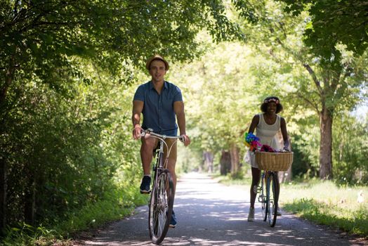 a young man and a beautiful African American girl enjoying a bike ride in nature on a sunny summer day