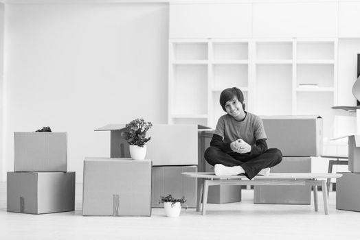 happy little boy sitting on the table with cardboard boxes around him in a new modern home