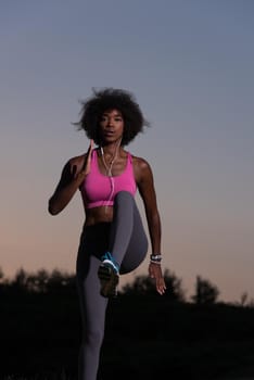 Young healthy black woman is doing stretching exercise relaxing and warm up after jogging and running in the nature beautiful summer evening