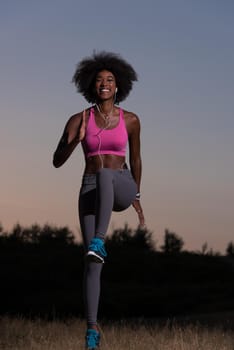 Young healthy black woman is doing stretching exercise relaxing and warm up after jogging and running in the nature beautiful summer evening