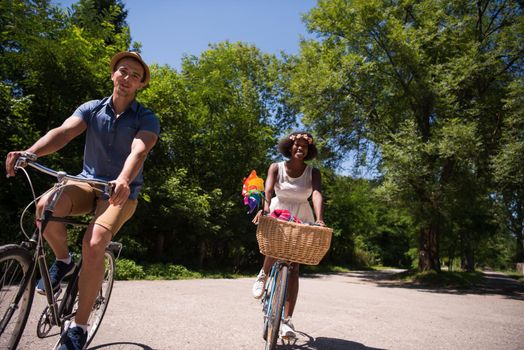 a young man and a beautiful African American girl enjoying a bike ride in nature on a sunny summer day