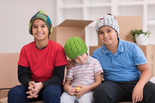 portrait of happy young boys with cardboard boxes around them in a new modern home