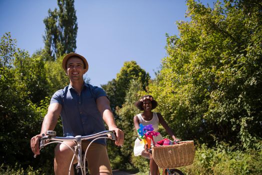 a young man and a beautiful African American girl enjoying a bike ride in nature on a sunny summer day