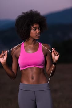portrait of a young beautiful african american woman with headphones jogging in nature beautiful summer night