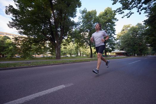 healthy athlete man jogging at morning on empty  roat in the city