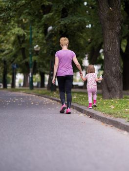 young sporty mother and little daughter jogging in a city park outdoor sports and fitness