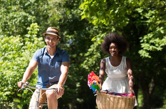 a young man and a beautiful African American girl enjoying a bike ride in nature on a sunny summer day