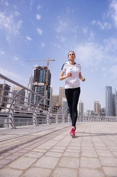 Running in city park. Woman runner outside jogging at morning with Dubai urban scene in background