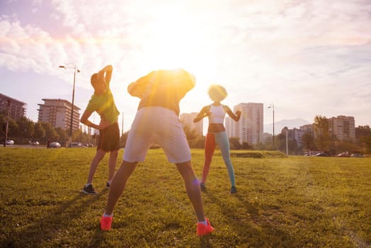 multiethnic group of young people stretching before running with the sunrise in the city