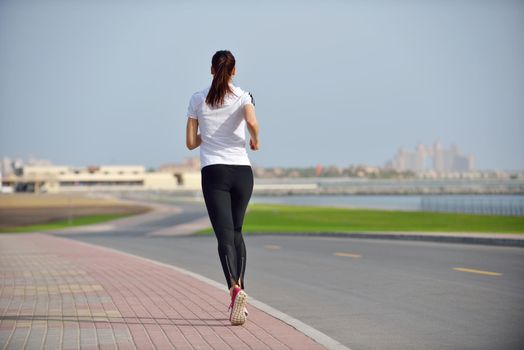 Running in city park. Woman runner outside jogging at morning with Dubai urban scene in background