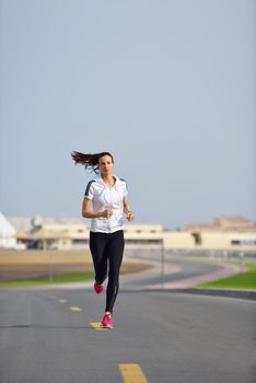 Running in city park. Woman runner outside jogging at morning with Dubai urban scene in background