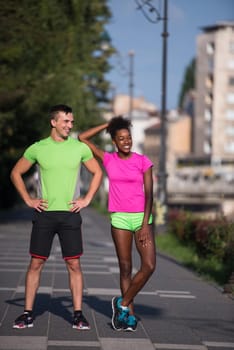 portrait of young multietnic jogging couple ready to run on fresh morning in the city