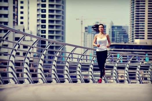 Running in city park. Woman runner outside jogging at morning with Dubai urban scene in background