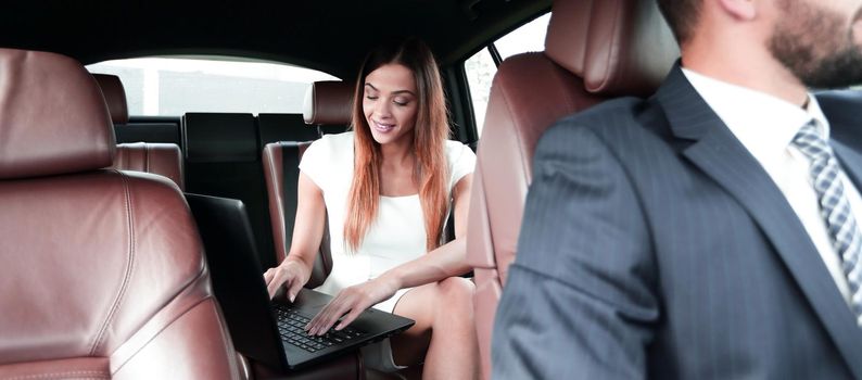 Female entrepreneur working during travelling to office in a luxury car.