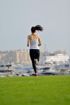 Running in city park. Woman runner outside jogging at morning with Dubai urban scene in background