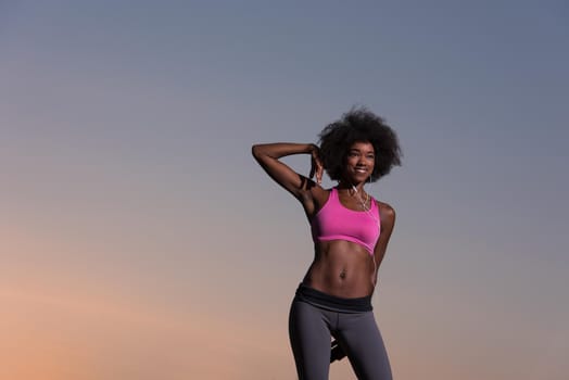 Young healthy black woman is doing stretching exercise relaxing and warm up after jogging and running in the nature beautiful summer evening