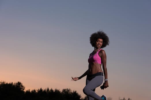 Young healthy black woman is doing stretching exercise relaxing and warm up after jogging and running in the nature beautiful summer evening