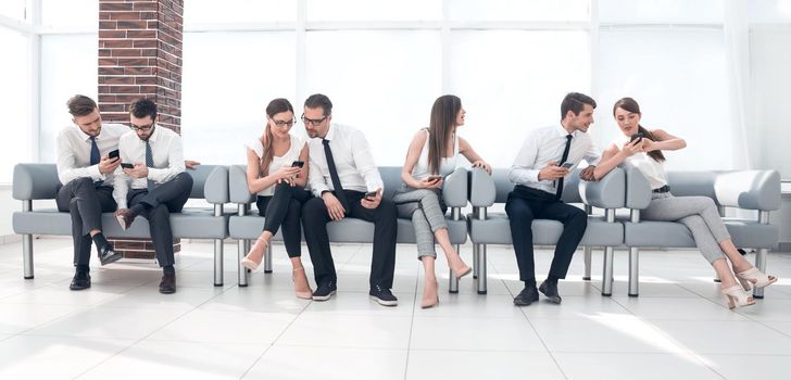 group of employees use smartphones while sitting in the office lobby.photo with copy space