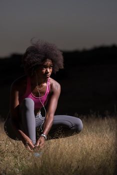 young African american woman runner tightening shoe lace in nature  Fitness, people and healthy lifestyle