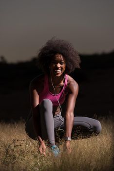 young African american woman runner tightening shoe lace in nature  Fitness, people and healthy lifestyle