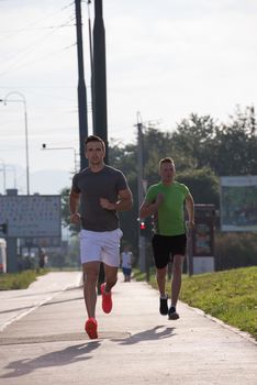 athletic young men enjoy running while the sun rises over the city