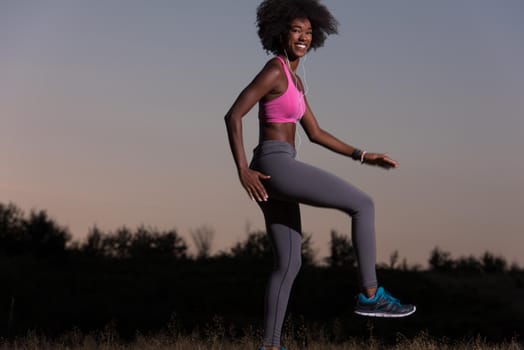 Young healthy black woman is doing stretching exercise relaxing and warm up after jogging and running in the nature beautiful summer evening