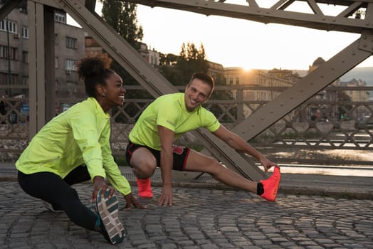 Young multiethnic jogging couple warming up and stretching before morning running in the city