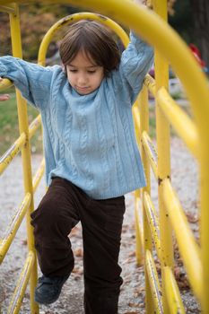 cute little boy having fun in playground park on cludy autum day