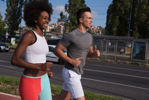 multiethnic group of young people on the jogging beautiful morning as the sun rises in the streets of the city