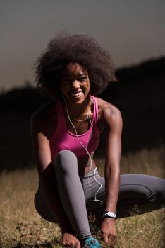 young African american woman runner tightening shoe lace in nature  Fitness, people and healthy lifestyle